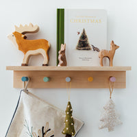 Wooden shelf with decorative items including a moose figurine, a book titled 'Christmas', and small tree ornaments.
