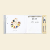 Open book of WIshy Washy Color Reveal with illustrations of a paint palette, text, and a pen on a beige background
