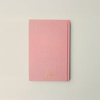 Pink notebook with gold text on a light gray background