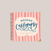 Calligraphy practice workbook with pink striped cover on a light gray background