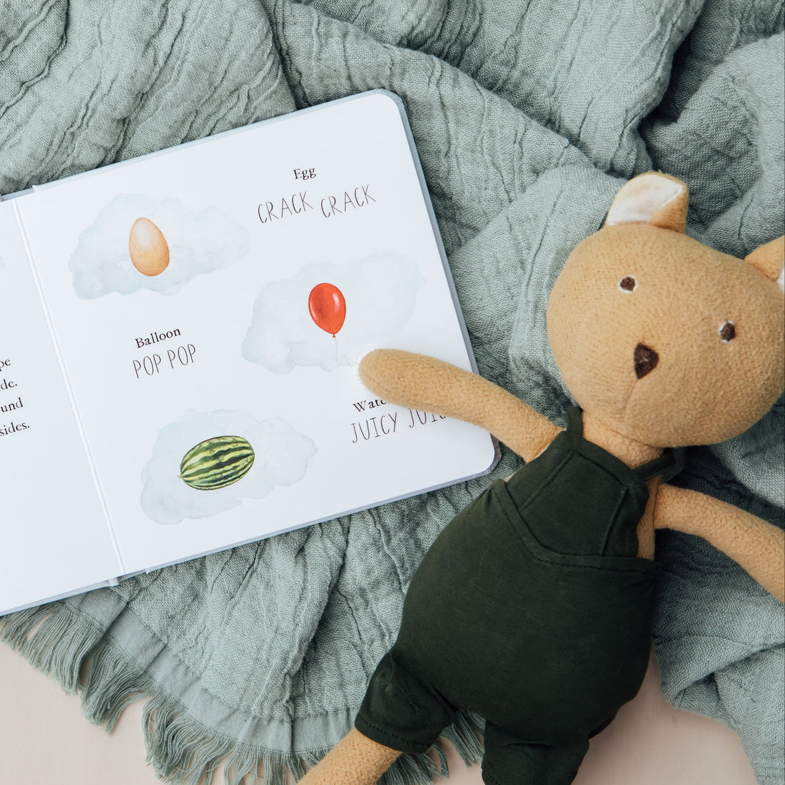 Children's book with illustrations of fruits and a teddy bear on a textured surface
