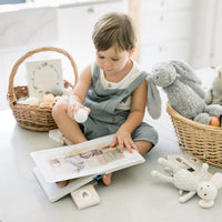 Child reading a book with toys on a light-colored floor