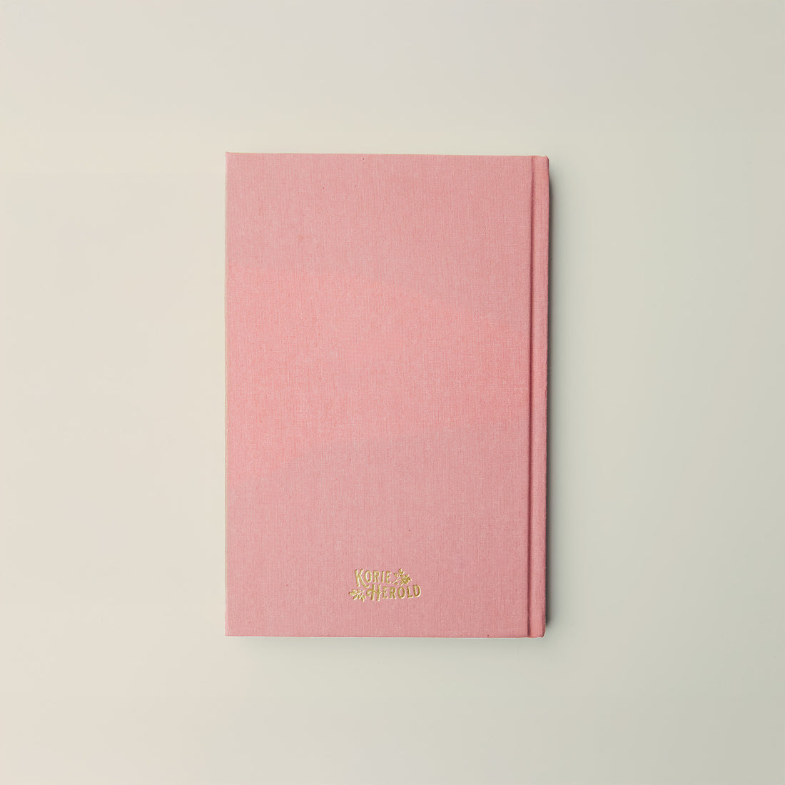 Pink notebook with gold text on a light gray background