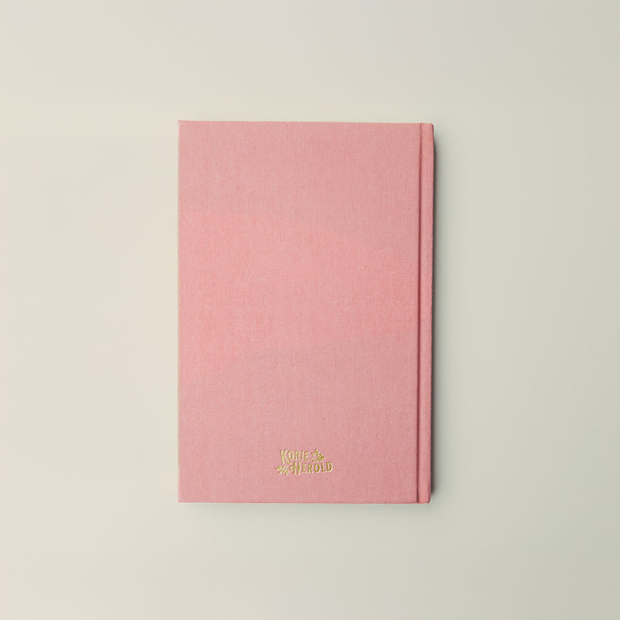 Pink notebook with gold text on a light gray background