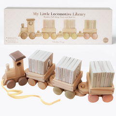 My Little Locomotive Library wooden pull-along train and book set by Tabitha Paige, shown with its gift box above. The natural wood engine pulls three cars with muted brown, tan, sage, and pink wheels, each carrying five miniature board books on topics like farm animals, ocean animals, dinosaurs, and space, with a yellow ribbon pull string.