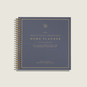A spiral-bound home planner book titled 'The Beautifully Organized Home Planner' by Nikki Boyd, featuring a slate blue cover with gold text and border details, shown on a light beige background.