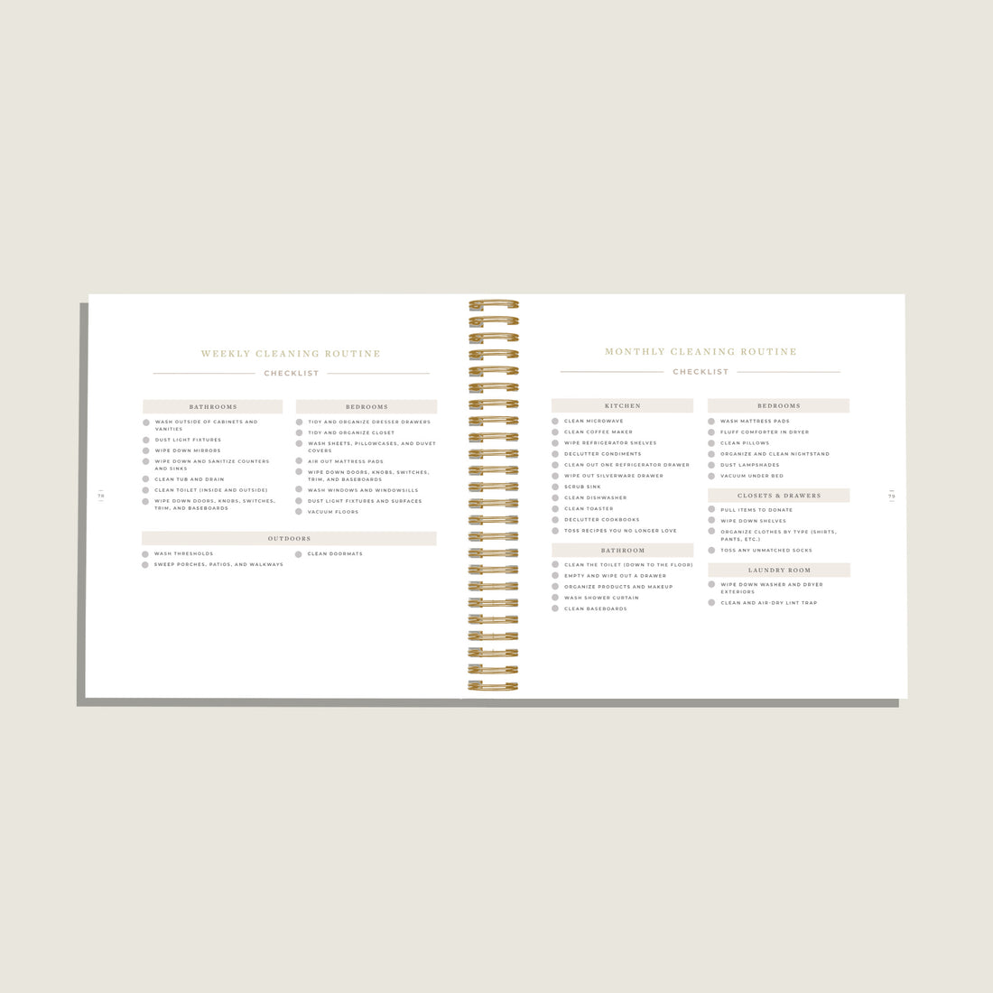 An open spiral-bound planner or notebook showing two printed pages with cleaning routine tables and headings, photographed on a light warm gray background.